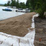 Prace budowalne przy budowie Eko Plaży Giżycko. Zdjęcie przedstawia nasypywanie piasku pod przyszłą plażę.