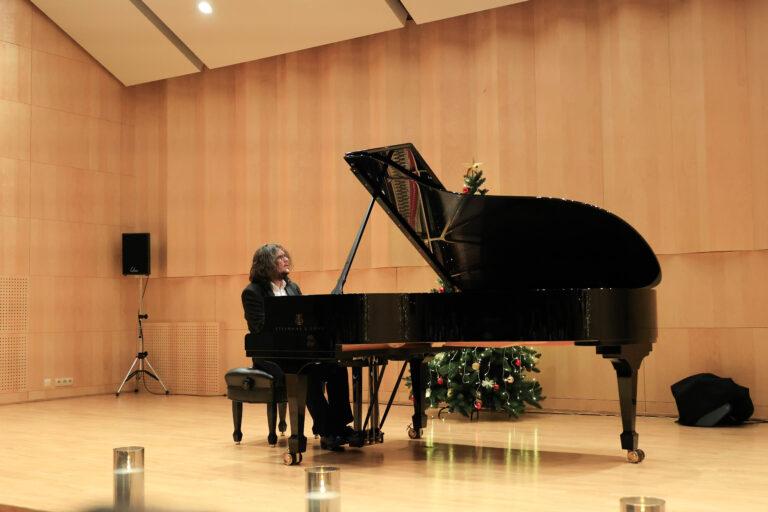 Pianista Jakub Kuszlik podczas recitalu w Sali koncertowej Państwowej Szkoły Muzycznej I stopnia w Giżycku. Na pierwszym planie czarny fortepian Steinway & Sons.